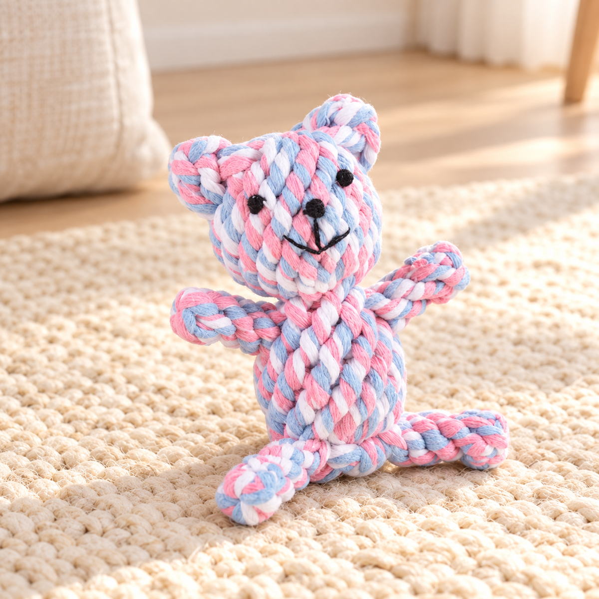 Pastel pink, blue and white Rope Buddy Bear dog toy on a cream rug